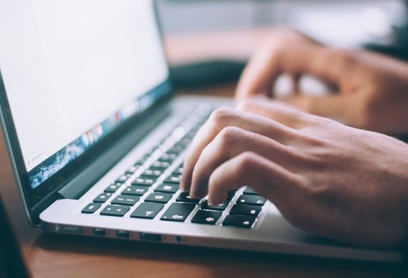 Person tippt auf einer Tastatur am Laptop